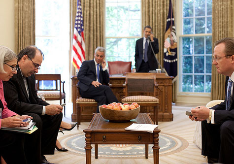 Obama on phone in oval office with staff waiting